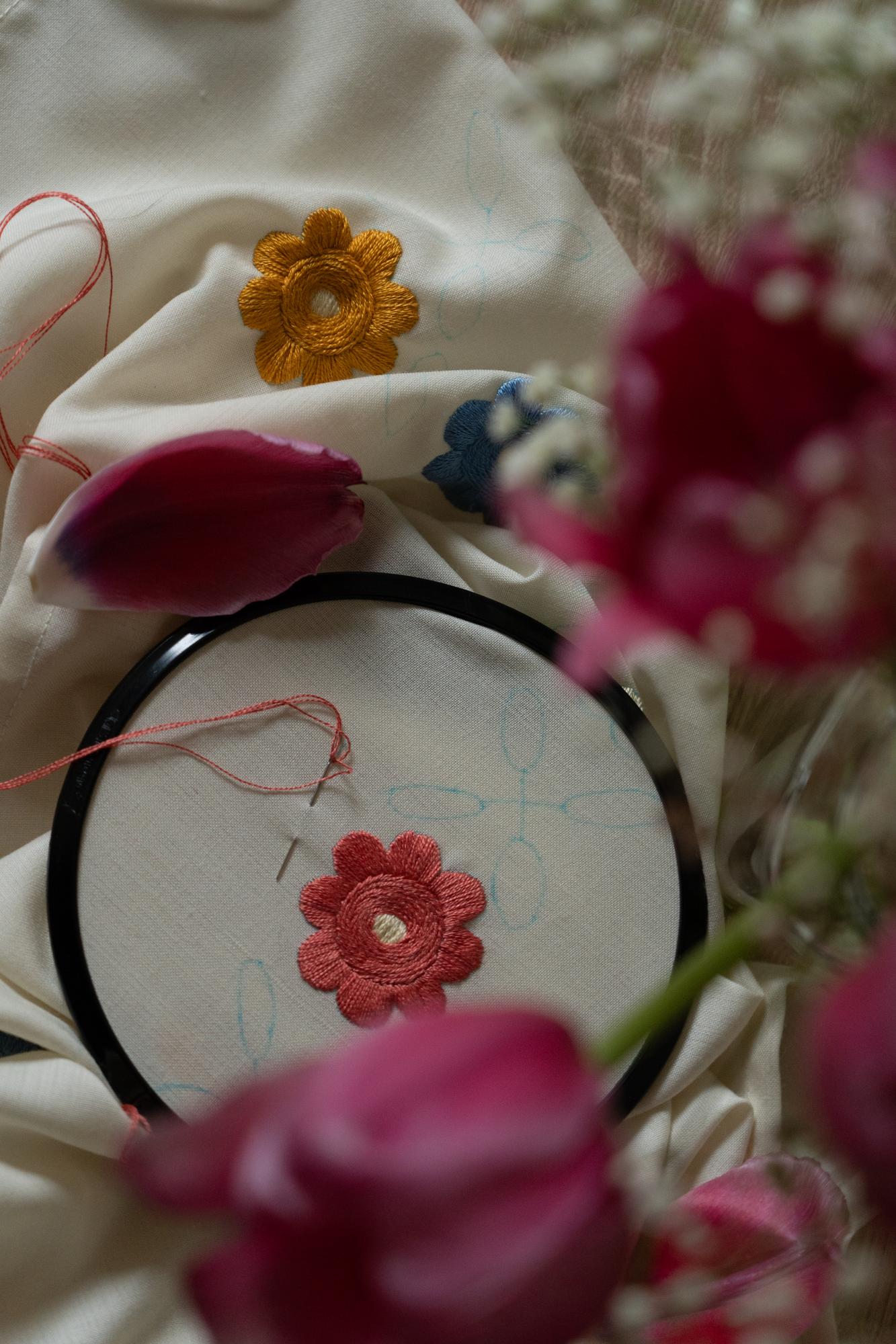 Mano che ricama un fiore su lino